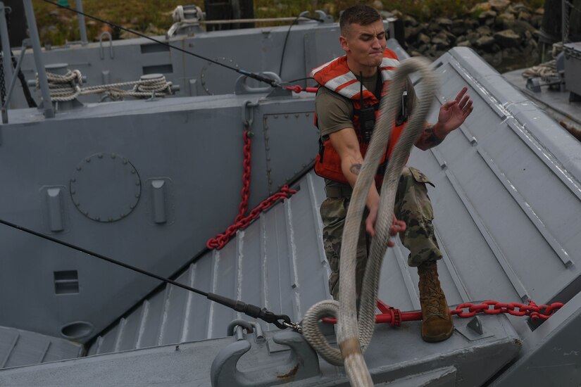 U.S. Army Spc. Austin McCaffrey, 73rd Transportation Company, 10th Trans. Battalion, 7th Trans. Brigade (Expeditionary) sea pay clerk, catches a rope to secure a Landing Craft Mechanized, Mark 8 for towing training at Joint Base Langley-Eustis, Virginia, Nov. 5, 2018. The 73rd Trans. Co. maintains the only 800-series Large Tug boat in the Army, as well as two 900-series Small Tugs, a floating 100-ton Barge Derrick Crane and a 188k/gal Fuel Barge out of Third Port. (U.S. Air Force photo by Senior Airman Derek Seifert)