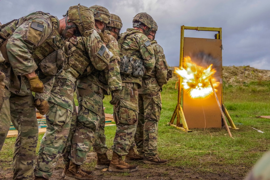 Paratroopers stand together in line as they detonate a charge in a mock door.