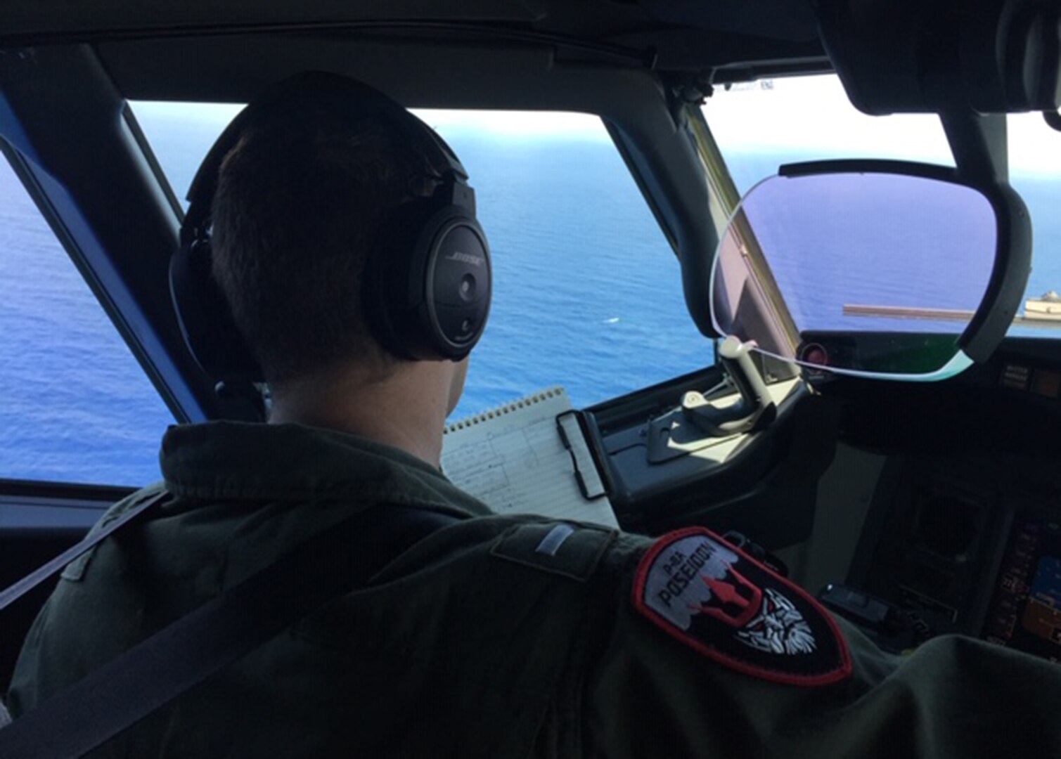 Lt. j.g. Steven Mcintyre, assigned to Ptrol Squadron (VP) 16, takes notes from the flight station of a maritime patrol aircraft P-8A Poseidon.