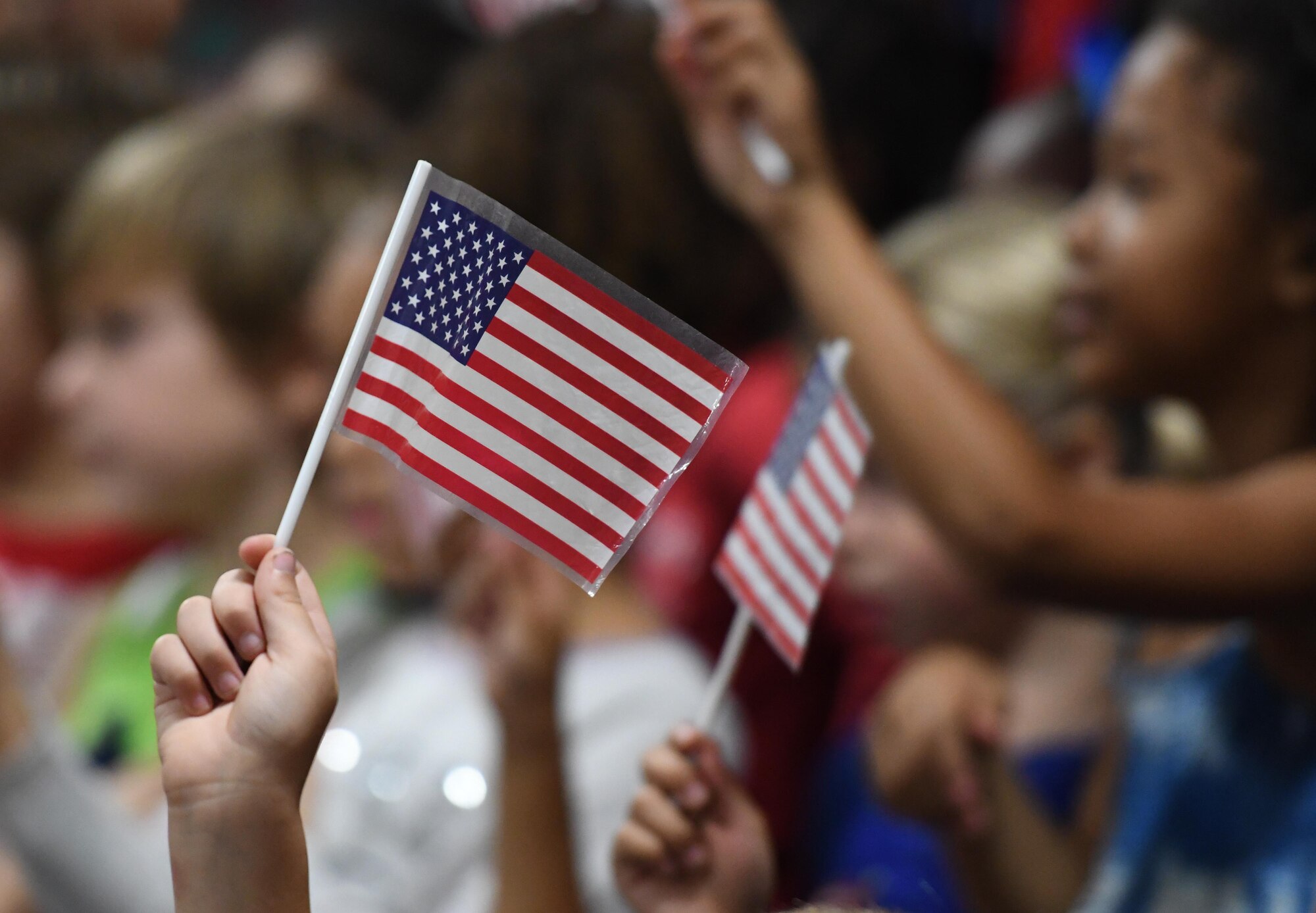 Students at Jeff Davis Elementary School wave U.S. flags during a Veterans Day celebration in Biloxi, Mississippi, Nov. 8, 2018. During the event, students also recited the Pledge of Allegiance. Keesler Air Force Base leadership, honor guardsmen and base personnel attended the event. (U.S. Air Force photo by Kemberly Groue)