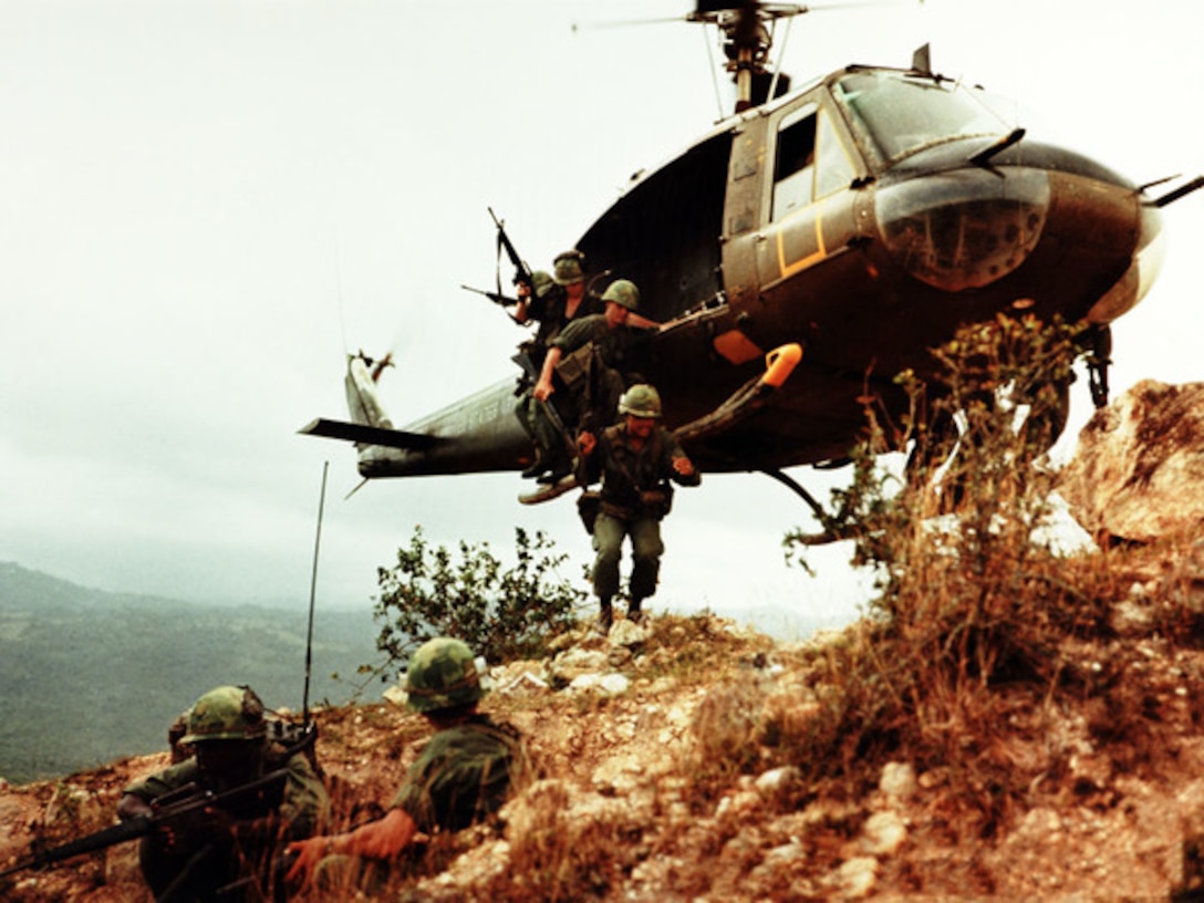 Soldiers jump out of a helicopter hovering close to the ground in South Vietnam.