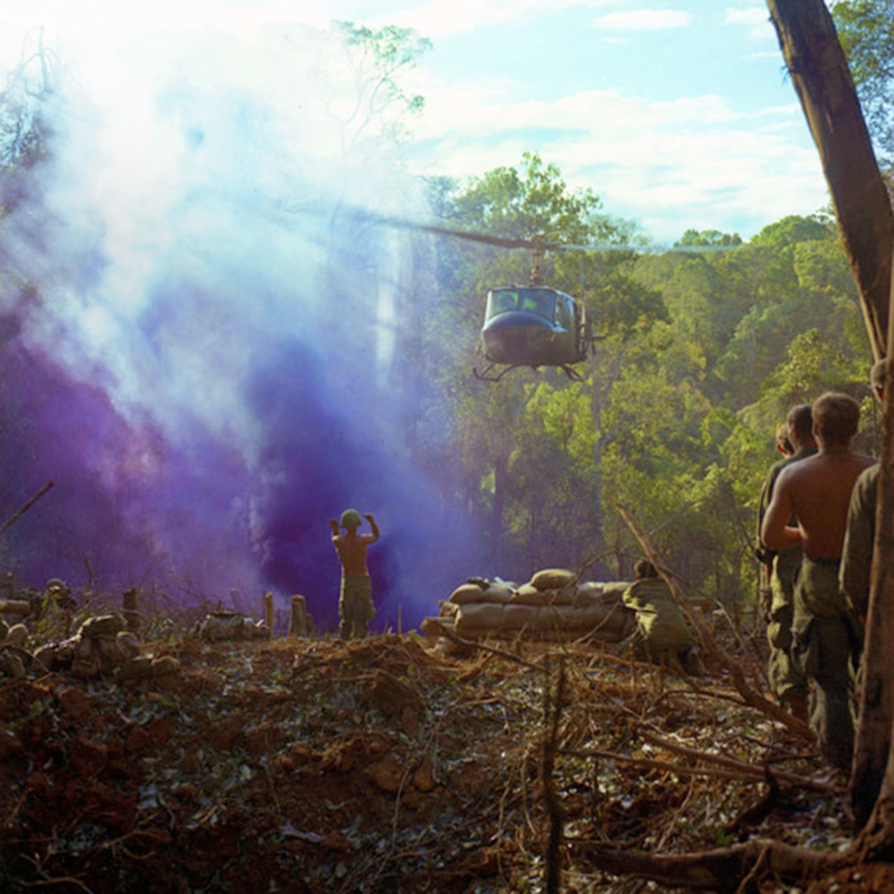 An Army helicopter hovers over a landing zone in South Vietnam, as soldiers stand by.