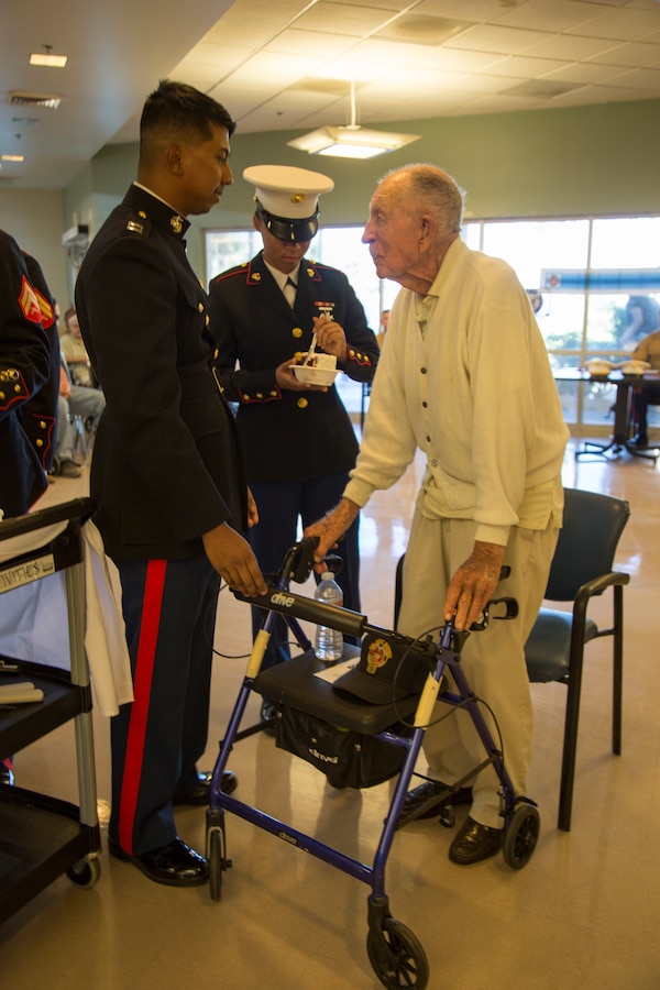 Captain Adam Rahman, Headquarters Company commanding officer, serves Marine Corps birthday cake to the oldest and youngest Marines present during the Corps' 243rd birthday celebration held at the Veterans Home of California - Barstow, Calif., Nov. 6. The oldest Marine is 98-year-old Guy "Dean" Smith who served in the Marine Corps from 1939 to 1948, while the youngest Marine is 18-year-old Lance Cpl. Alexas Toomer, who enlisted in December 2017.