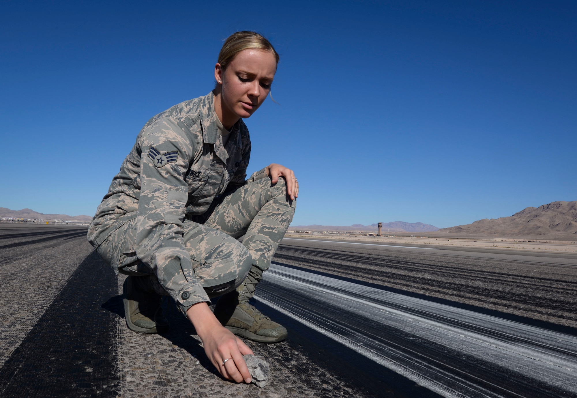 Senior Airman Sierra Rodwick, 57th Operations Support Squadron airfield management shift lead, removes foreign object and debris from a runway Oct. 15, 2018 on Nellis Air Force Base, Nevada. The professionalism and urgency demonstrated by airfield management on a daily basis are what keep Nellis a step above the rest. (U.S. Air Force photo by Airman Bailee A. Darbasie)