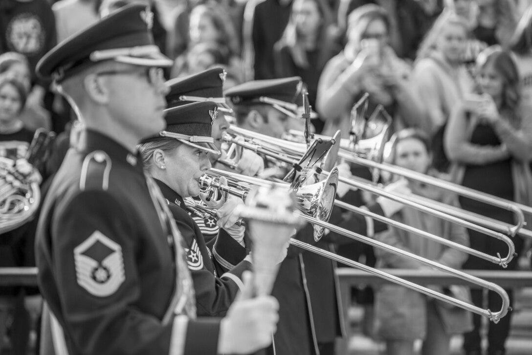 Airmen play trombone outside in front of an audience.