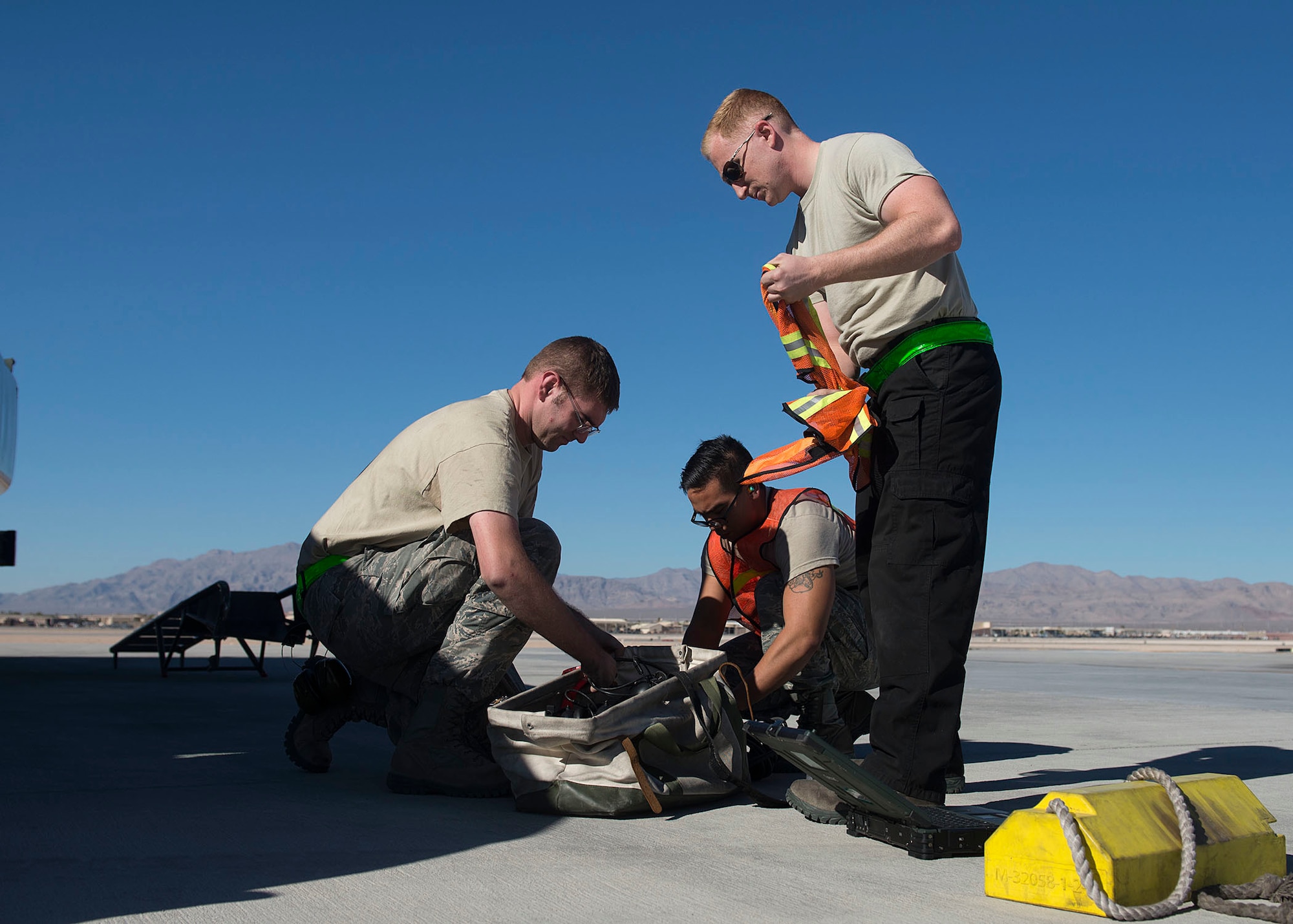 Staff Sgts. James Smith and Guy Hinton, 57th Aircraft Maintenance Squadron Raptor Aircraft Maintenance Unit dedicated crew chiefs, and Senior Airman Johnny Cruz, 57th AMXS Raptor AMU assistant DCC, prepared their gear on the flightline at Nellis Air Force Base, Nevada, Nov. 7, 2018. They performed a hot-pit refueling where an aircraft is refueled while still running to get the fighter jet back to the mission faster. (U.S. Air Force photo by Airman 1st Class Bryan T. Guthrie)