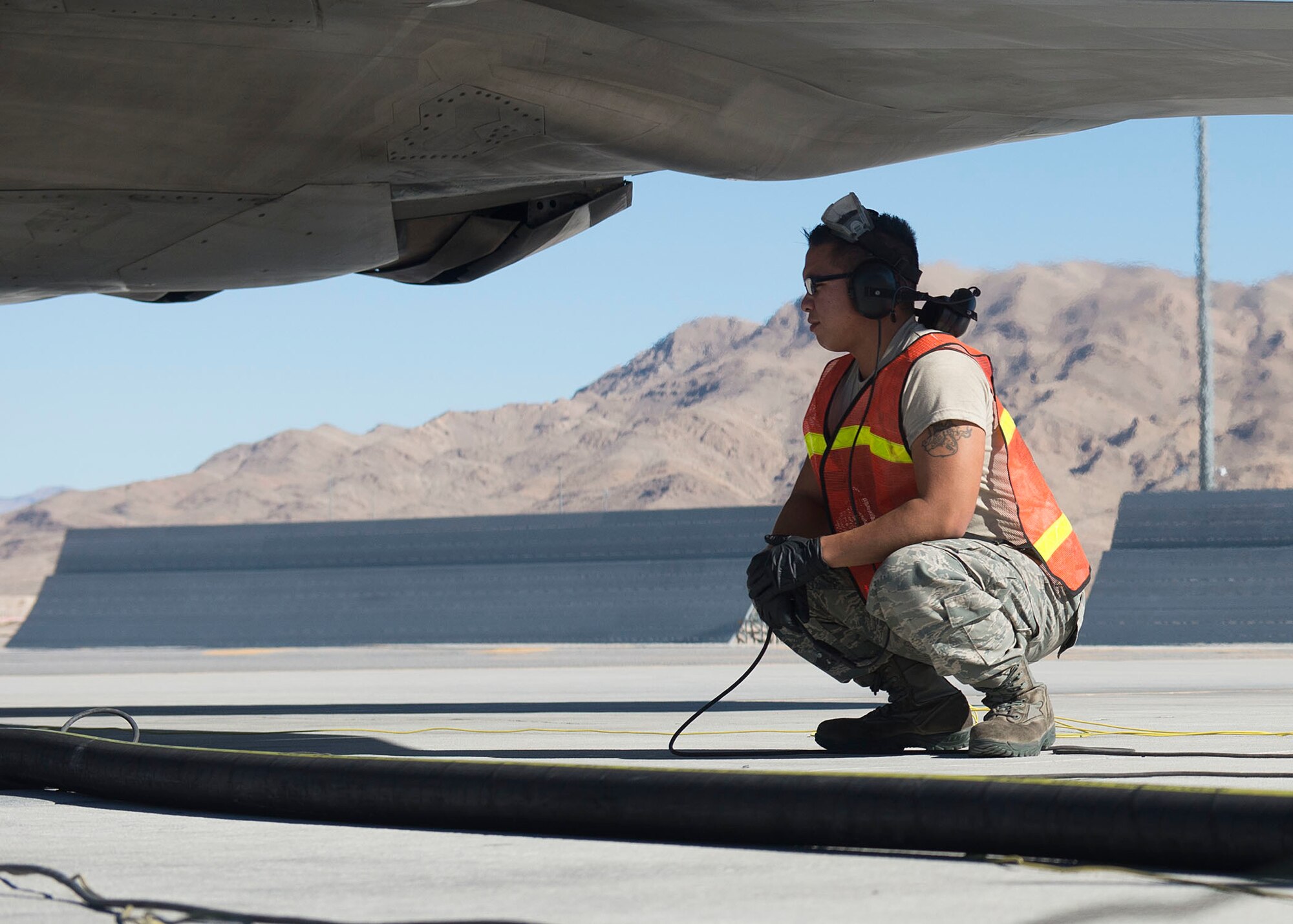 Senior Airman Johnny Cruz, 57th Aircraft Maintenance Squadron Raptor Aircraft Maintenance Unit assistant dedicated crew chief, watches as a jet gets refueled at Nellis Air Force Base, Nov. 7, 2018. Hot-pit refueling has to be done carefully because the jet is still running while simultaneously being refueled. (U.S. Air Force photo by Airman 1st Class Bryan T. Guthrie)