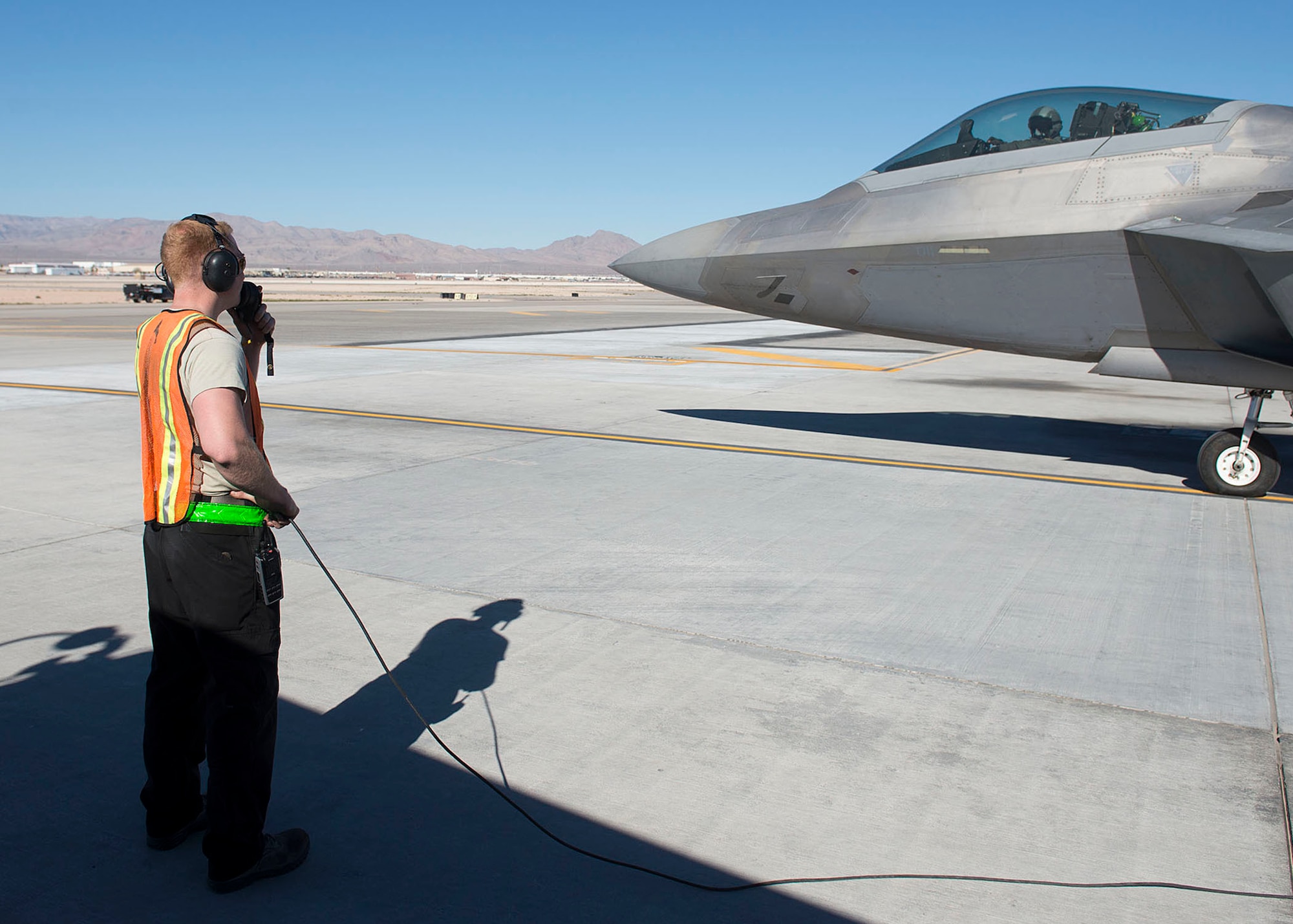 Staff Sgt. Guy Hinton, 57th Aircraft Maintenance Squadron Raptor Aircraft Maintenance Unit Dedicated Crew Chief, directs a F-22 Raptor fighter jet at Nellis Air Force Base, Nevada, Nov. 7, 2018. The 57th AMXS accomplishes on-equipment maintenance to include aircraft servicing, before and after flight inspections, launch and recovery, munitions loading and accomplishment of schedule/unscheduled maintenance requirements.(U.S. Air Force photo by Airman 1st Class Bryan T. Guthrie)