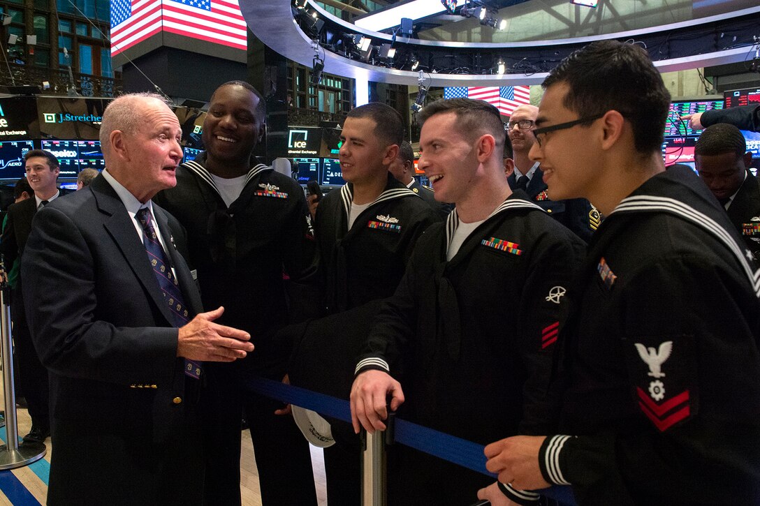 Sailors speak to a retired Marine Corps colonel as they stand on the floor of the New York Stock Exchange.