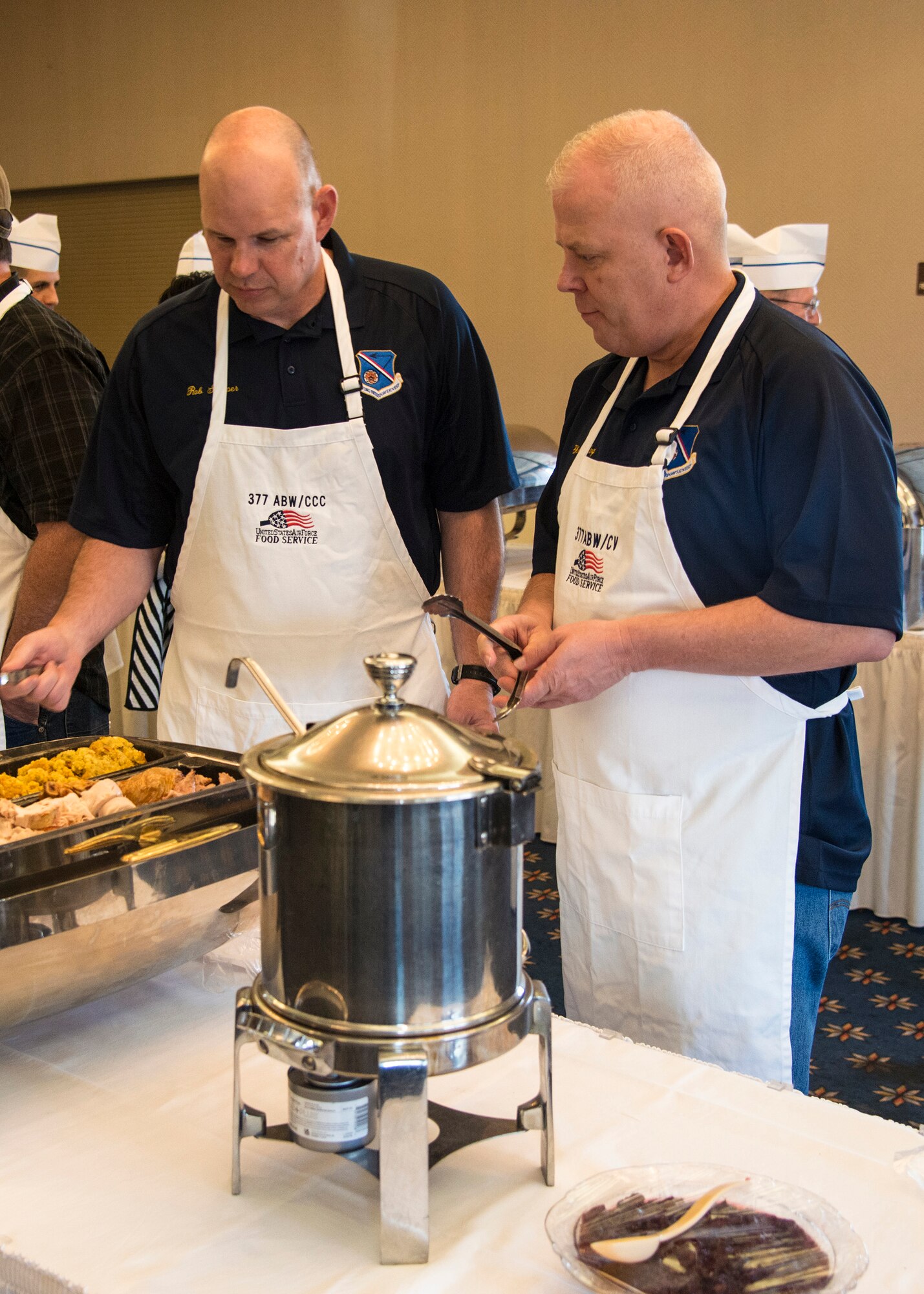 377th Air Base Wing Command Chief Master Sgt. Robert Stamper (left), and 377th Vice Commander Col. Christopher King prepare to serve a Thanksgiving luncheon Oct. 10 at the Mountain View Club. This lunchoen in years past was the traditional event scheduled for the families of deployed members, but was opened this year to the rest of Team Kirtland to increase support for deployed families. Patrons were treated to a traditional Thanksgiving lunch followed by entertainment from Tall Paul the Magician.