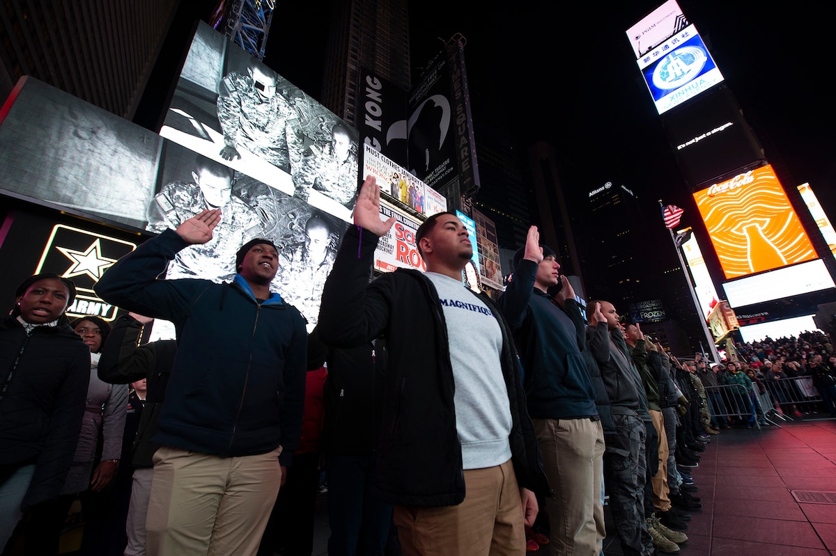 Enlistees raise their hands during a mass enlistment ceremony in Times Square in New York.