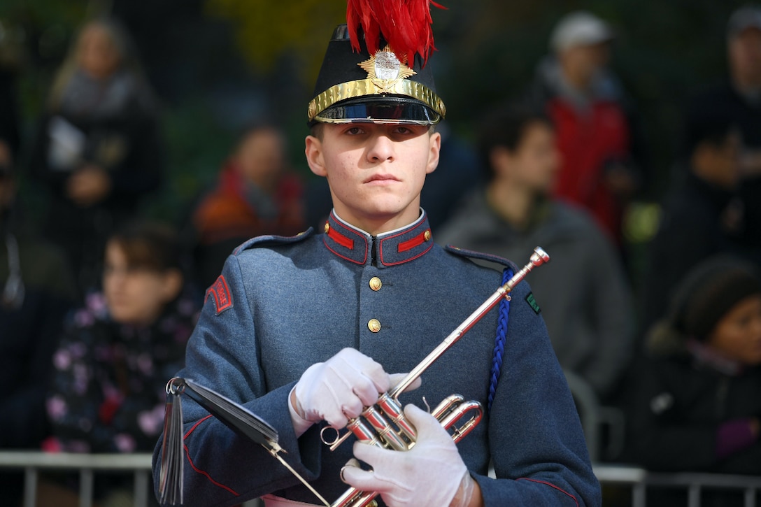 A trumpeter in uniform holds a trumpet.