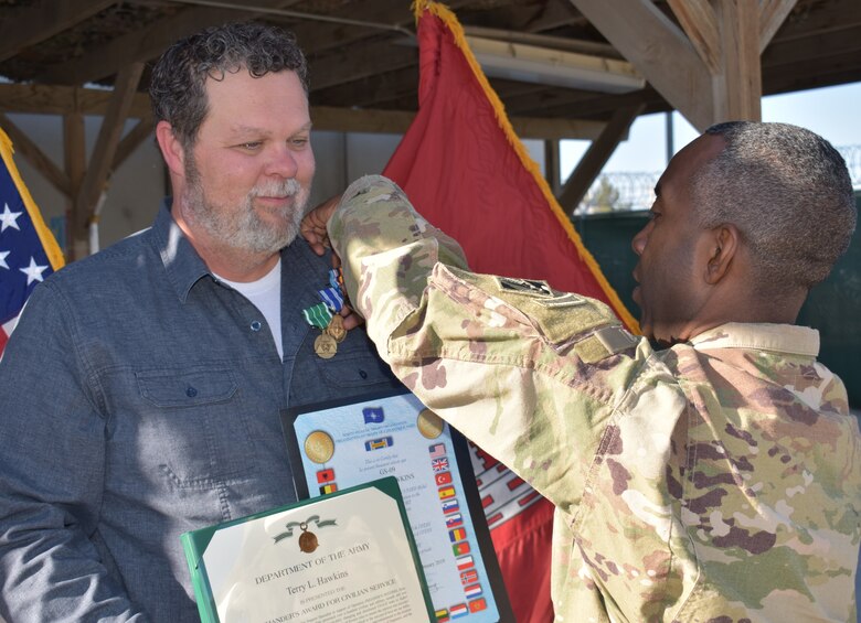 Afghanistan District Commander, Colonel Jason Kelly presents Terry “Hawk” Hawkins with the NATO, Global War on Terrorism, and Commanders award for civilian service as the District bids him farewell and Tulsa District receives their team member back.