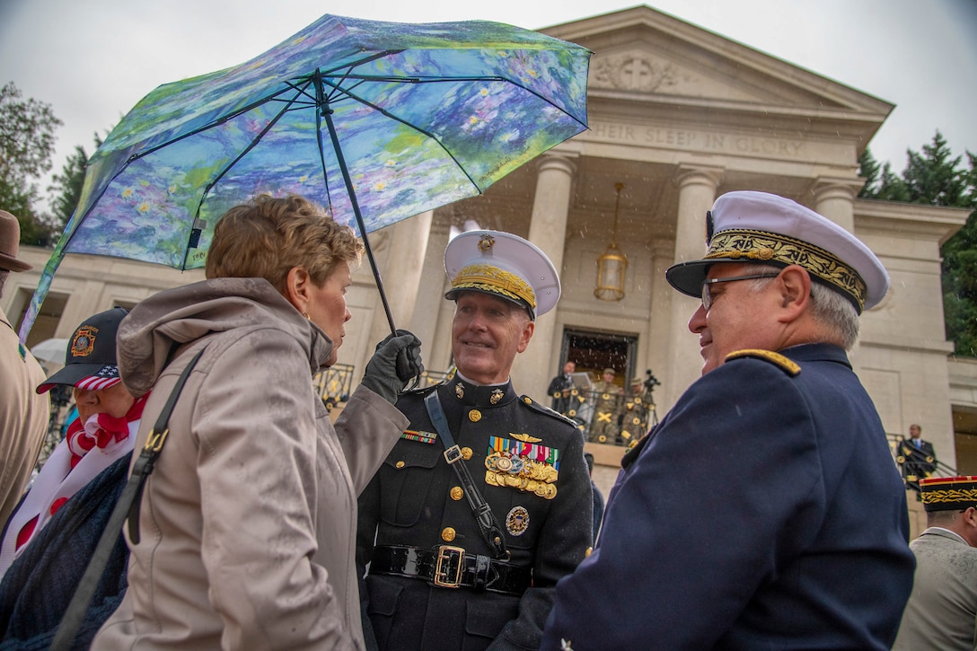 Marine Corps Gen. Joe Dunford, chairman of the Joint Chiefs of Staff, stands next to a woman holding an umbrella and a man