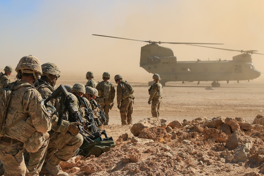 A group of troops line up behind helicopter