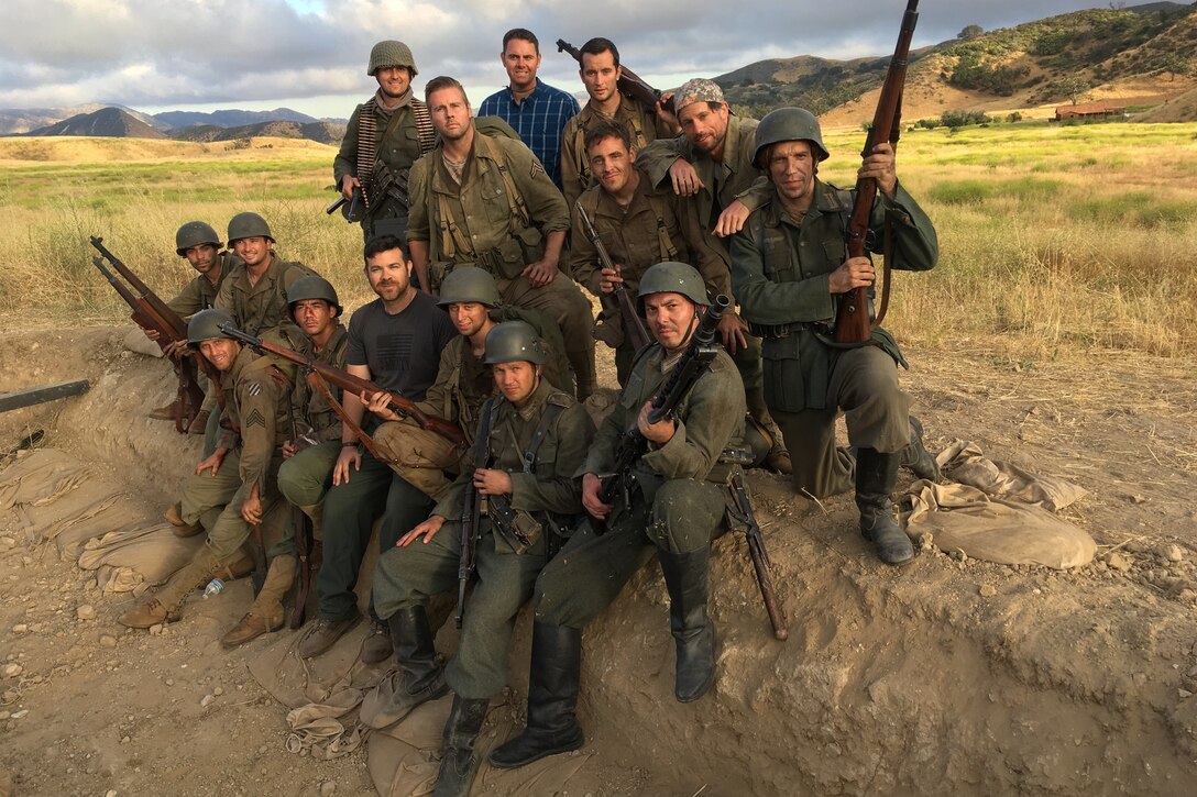 Men dressed as World War II soldiers pose in field.