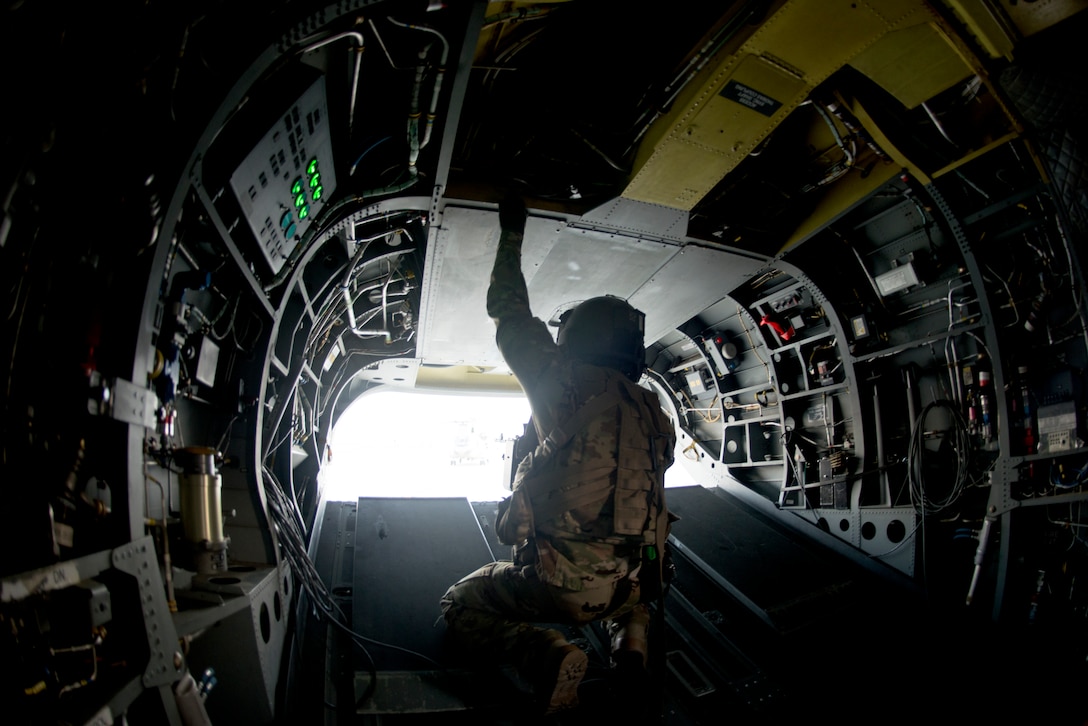Airman kneels inside aircraft as gate opens
