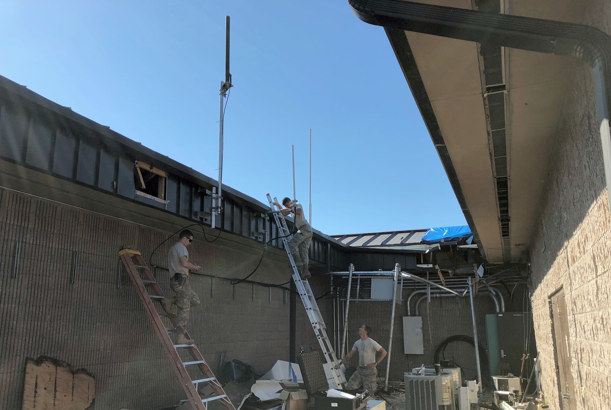 From left: Tech. Sgt. Skyler Shull, Airman Hunter Benson and Staff Sgt. Charlie Hegwer, 85th Engineer Installation Squadron, install three recycled antennae's on fabricated mounts for the Tyndall Enterprise Live Mission Operations Center facility at Tyndall Air Force Base, Florida, November 2, 2018. The TELMOC facility monitors flight status in the Gulf Coast and surrounding areas and had been damaged during Hurricane Michael. (U.S. Air Force Courtesy Photo)