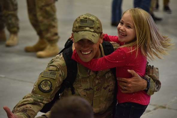 An Airman from the 819th Rapid Engineer Deployable Heavy Operational Repair Squadron Engineers (RED HORSE) hugs his children Nov. 5, 2018, at the airfields located on Malmstrom Air Force Base, Mont. The 819th RED HORSE U.S. Africa Command team shared in multi-agency base building efforts for Air Base 201 in Agadez, Niger, an expeditionary installation being constructed in one of the most remote regions in Africa. (U.S. Air Force photo by Airman 1st Class Jacob M. Thompson)