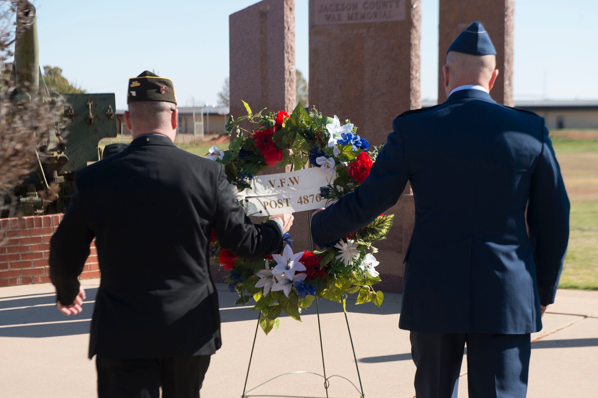 two men holding a wreath