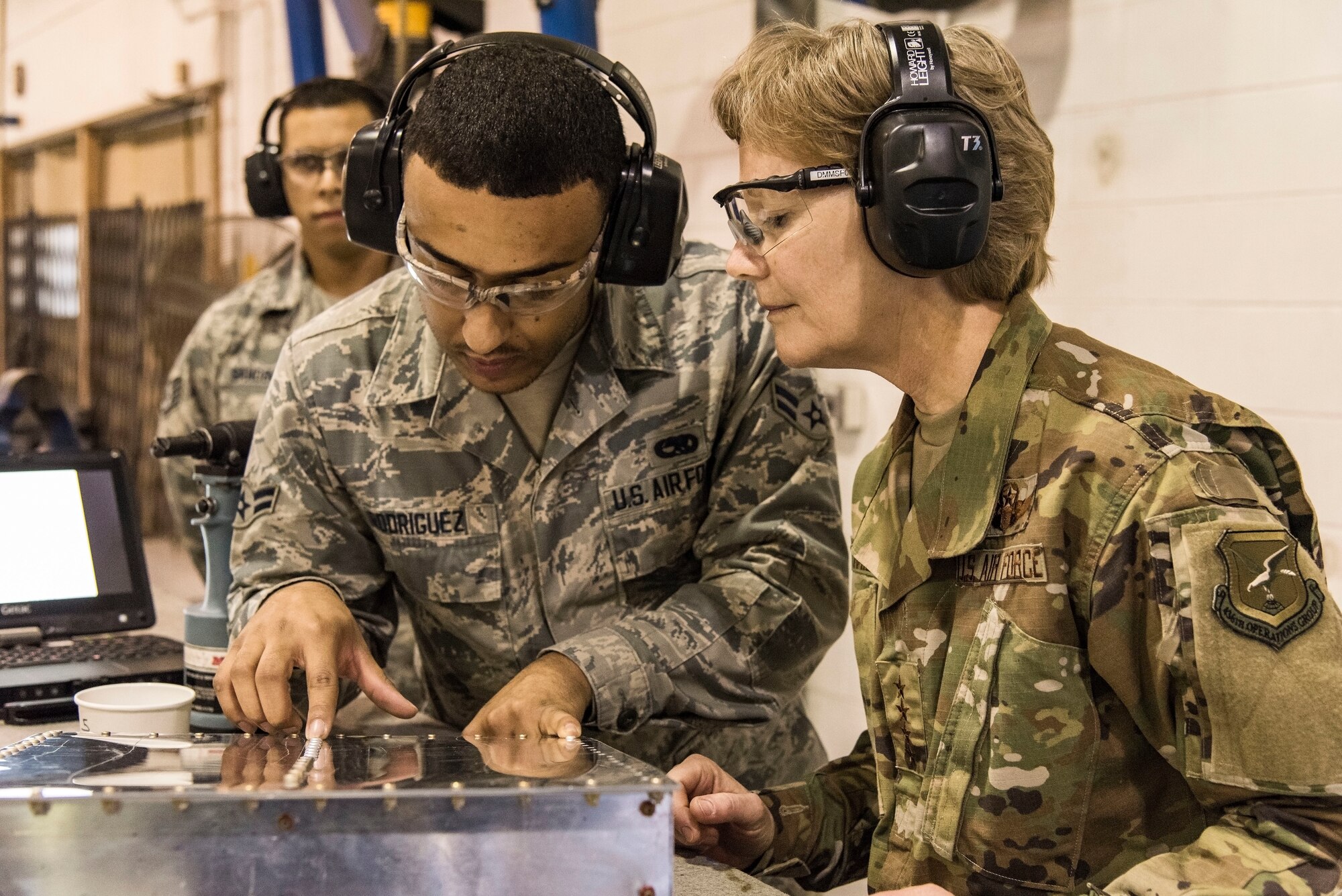 Airman 1st Class Reynaldo Rodriguez, right, 436th Maintenance Squadron aircraft structural maintenance journeyman, shows Gen. Maryanne Miller, left, Air Mobility Command commander, what a properly installed CherryMAX rivet looks like Nov. 7, 2018, at Dover Air Force Base, Del. Miller installed a rivet on a simulated aircraft part during her tour of the Fabrication Flight. (U.S. Air Force photo by Roland Balik)