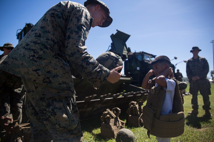 A Marine with Combat Logistics Battalion 31 helps a Tinian child into a flak jacket and helmet after a ceremony marking the end of the 31st Marine Expeditionary Unit’s mission as part of the U.S. Defense Support of Civil Authorities relief efforts on Tinian, Commonwealth of the Northern Mariana Islands, Nov. 14, 2018. Marines and Sailors with the 31st MEU and CLB-31 assisted the U.S. Federal Emergency Management Agency and local and civil authorities on Tinian to deliver aid to Tinians affected by Super Typhoon Yutu, which struck here Oct. 25 as the second strongest storm to ever hit U.S. soil. Marines and Sailors with the 31st MEU and CLB-31 arrived on Tinian Oct. 29-31 to lead relief efforts on Tinian in response to Yutu as part of Task Force-West. TF-W is leading the Department of Defense’s efforts to assist CNMI’s local and civil authorities provide critical assistance for citizens devastated by Yutu. The 31st MEU, the Marine Corps’ only continuously forward-deployed MEU, provides a flexible force ready to perform a wide-range of military operations across the Indo-Pacific region.