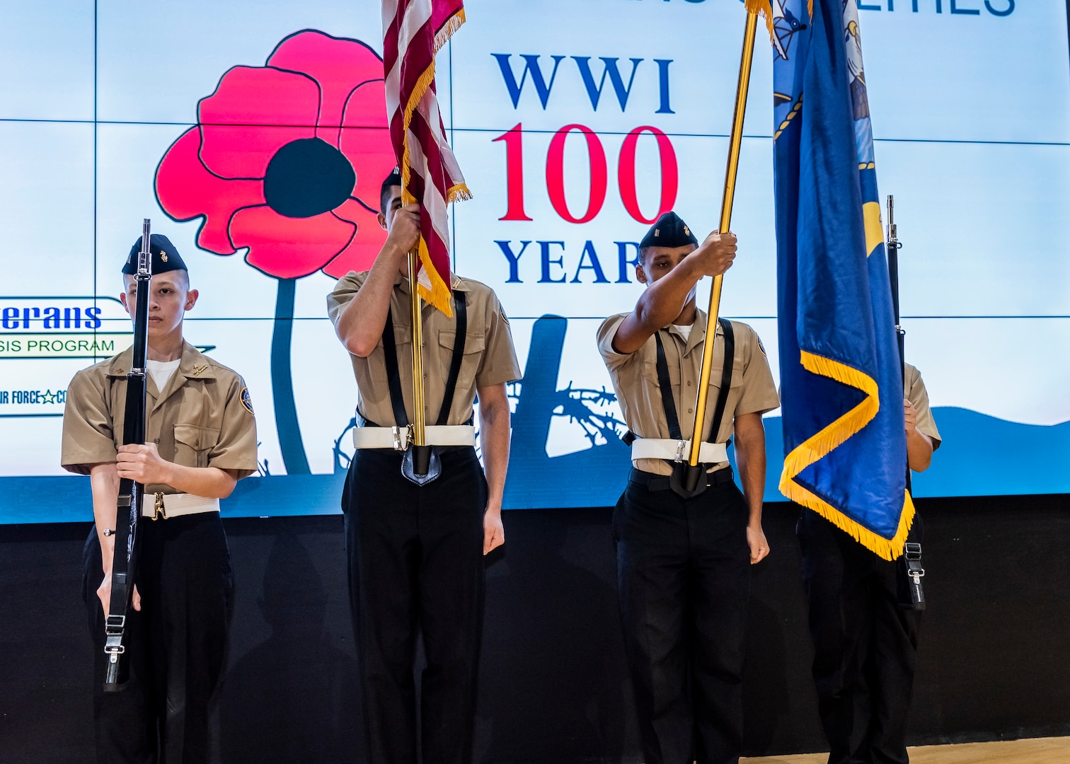 Four high school JROTC cadets present the colors during a program.