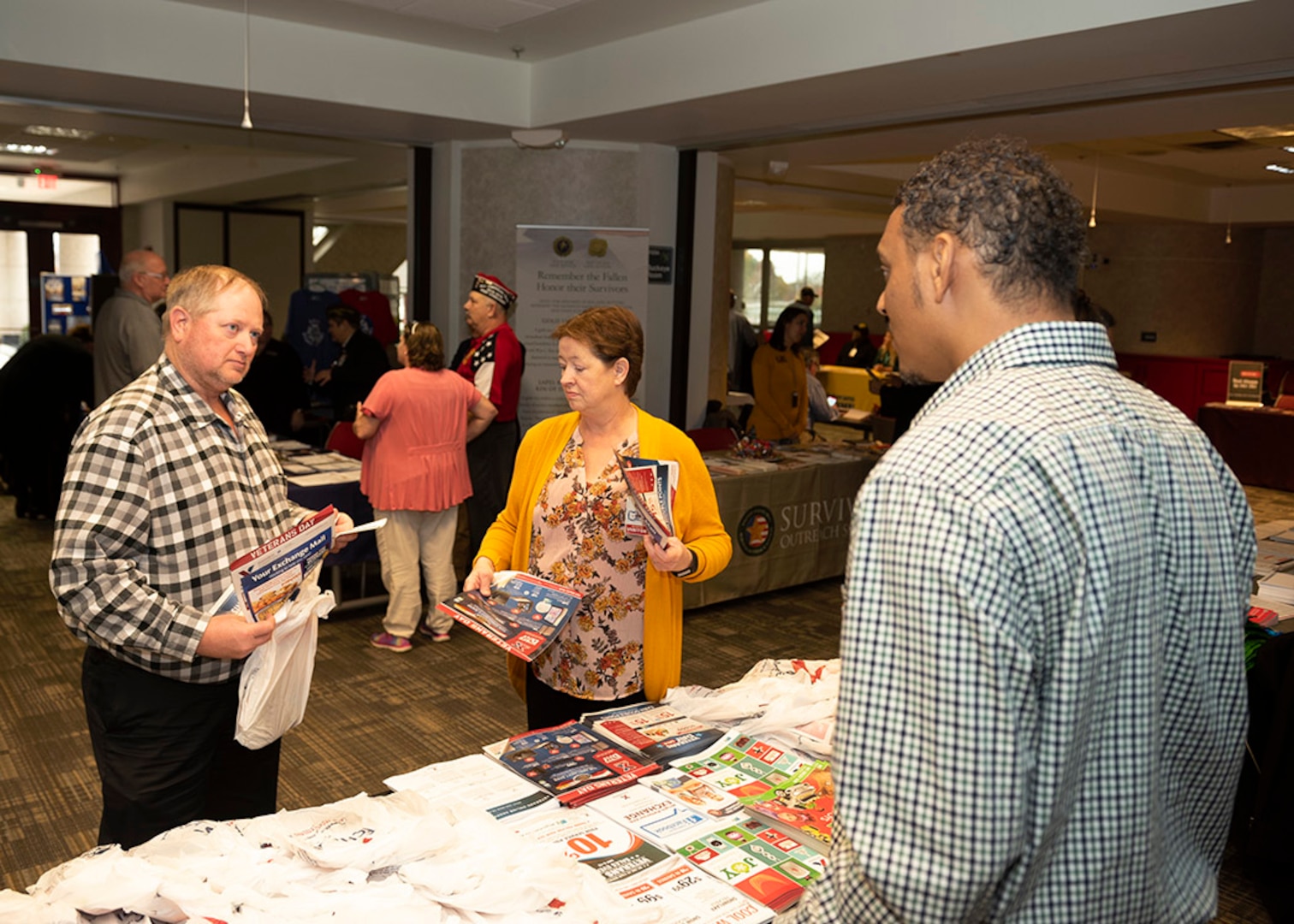 A vendor speaks with two associates during a Veterans Information Fair.