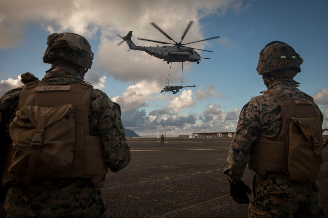 U.S. Marine Corps landing support specialists with Combat Logistics Battalion (CLB) 3 watch as a CH-53 Super Stallion helicopter assigned to Marine Heavy Helicopter Squadron (HMH) 463 takes off with a M777 towed 155 mm howitzer attached during a Helicopter Support Team (HST) exercise at Landing Zone Westfield, Marine Corps Base Hawaii, Oct. 22, 2018. The HST exercise is targeted to make the landing support specialists with Combat Logistics Battalion 3 and HMH-463 pilots more proficient in the case they need to quickly extract an object. (U.S. Marine Corps photo by Sgt. Zachary Orr)