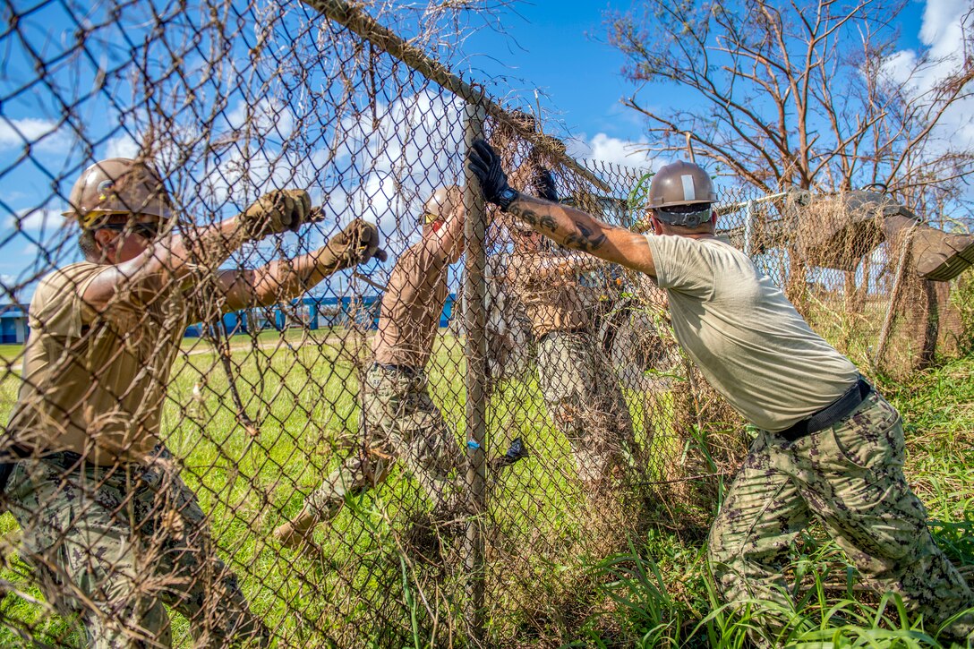Sailors fix a damaged fence.