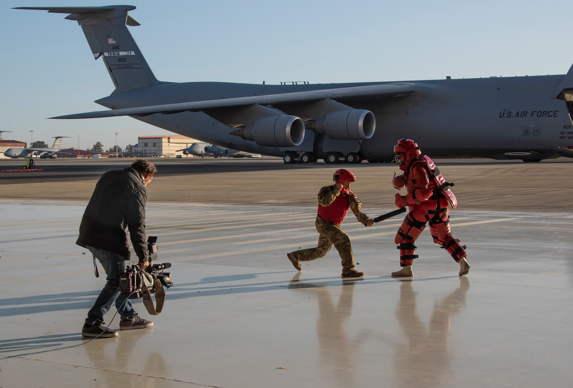 Terry Haggart, Good Day Sacramento, obtains footage of Senior Airman Uriel Mendoza and SrA Josue Jimenez, both with the 60th Security Forces Squadron, as they demonstrate Phoenix Raven defensive posture, Nov. 8, 2018, Travis Air Force Base, California. The Phoenix Raven program consists of teams of specially trained security forces personnel dedicated to providing security for AMC aircraft that transit high terrorist and criminal threat areas. (U.S. Air Force Photo by Heide Couch)