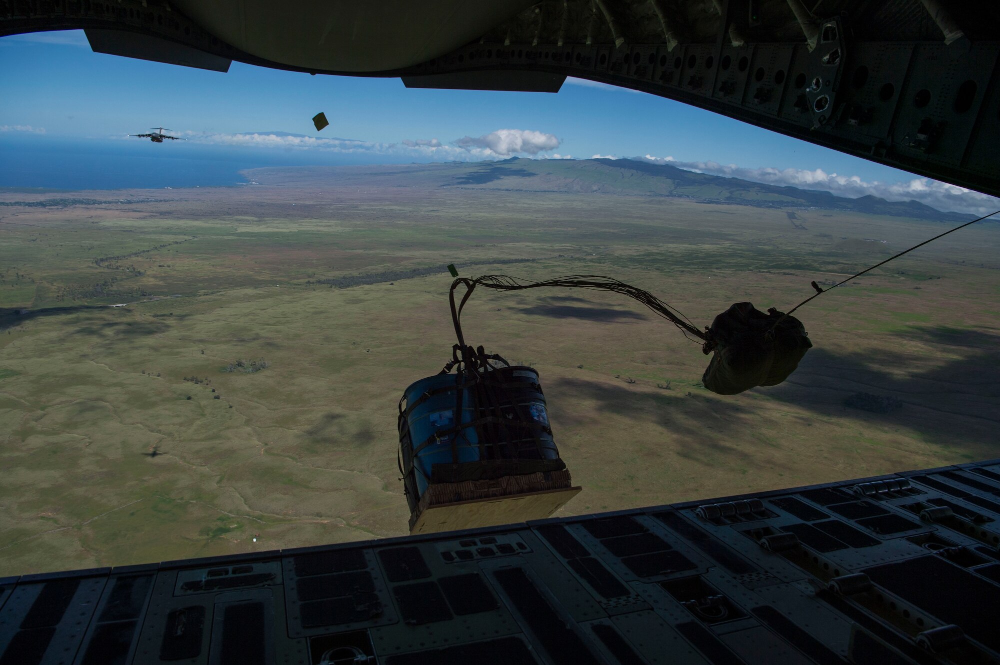 A container delivery system drops from a C-17 Globemaster III, assigned to Joint Base Pearl Harbor-Hickam, Hawaii, during Big Island Drop Week, at the Pohakuloa Training Area on Hilo, Hawaii Nov. 7, 2018. During Big Island Drop Week aircrews release container delivery system bundles to simulate dropping supplies to personnel on the ground. (U.S. Air Force photo by Tech. Sgt. Heather Redman)