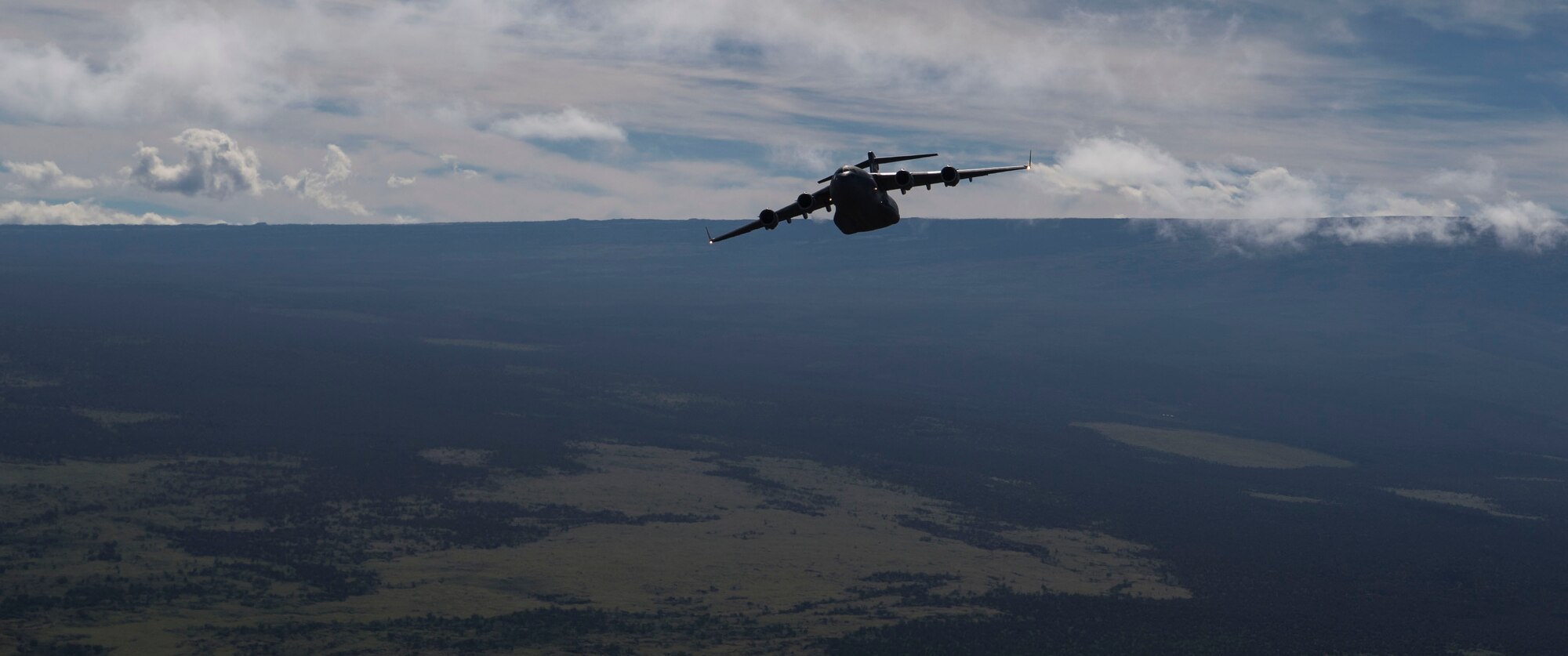 A C-17 Globemaster III, assigned to Joint Base Pearl Harbor-Hickam, Hawaii, flies above the Pohakuloa Training Area during Big Island Drop Week, on Hilo, Hawaii Nov. 7, 2018. Big Island Drop Week allowed aircrews to conduct mission planning and airdrop training in an environment that is not available Oahu, Hawaii. (U.S. Air Force photo by Tech. Sgt. Heather Redman)