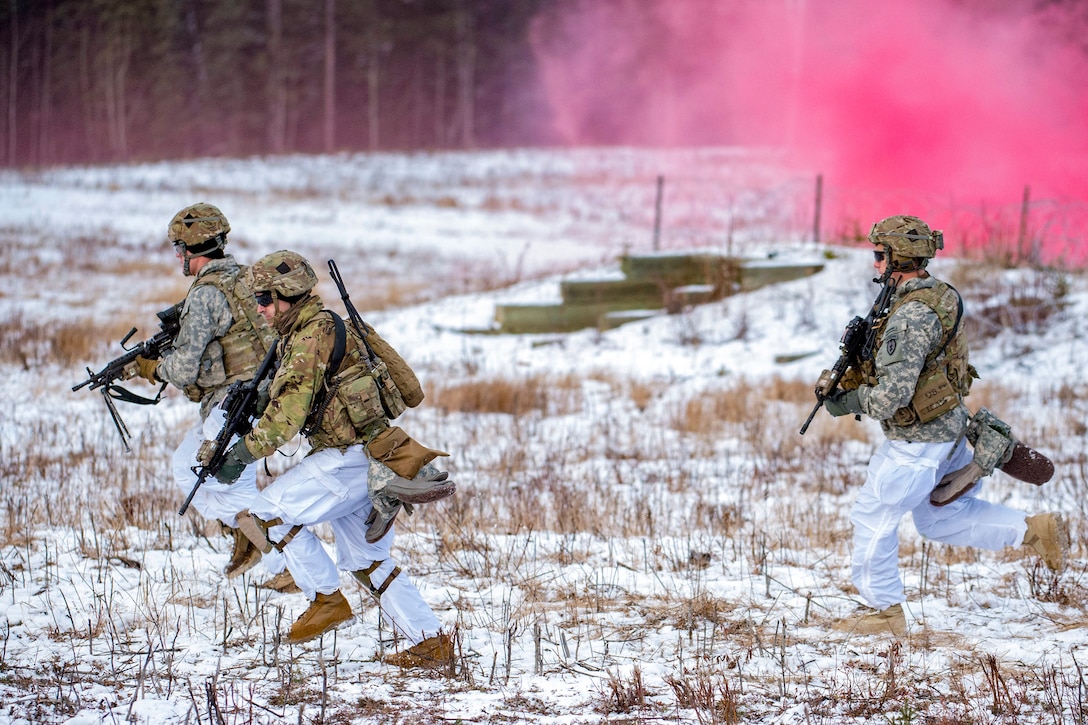 Three paratroopers run across snowy terrain with pink smoke in the background