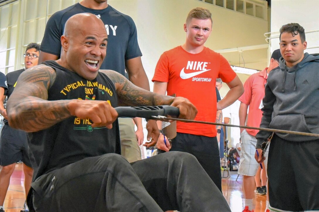 An Army vet rows on a machine while others watch.