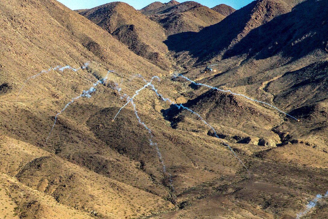 A helicopter fires multiple weapons over a valley.