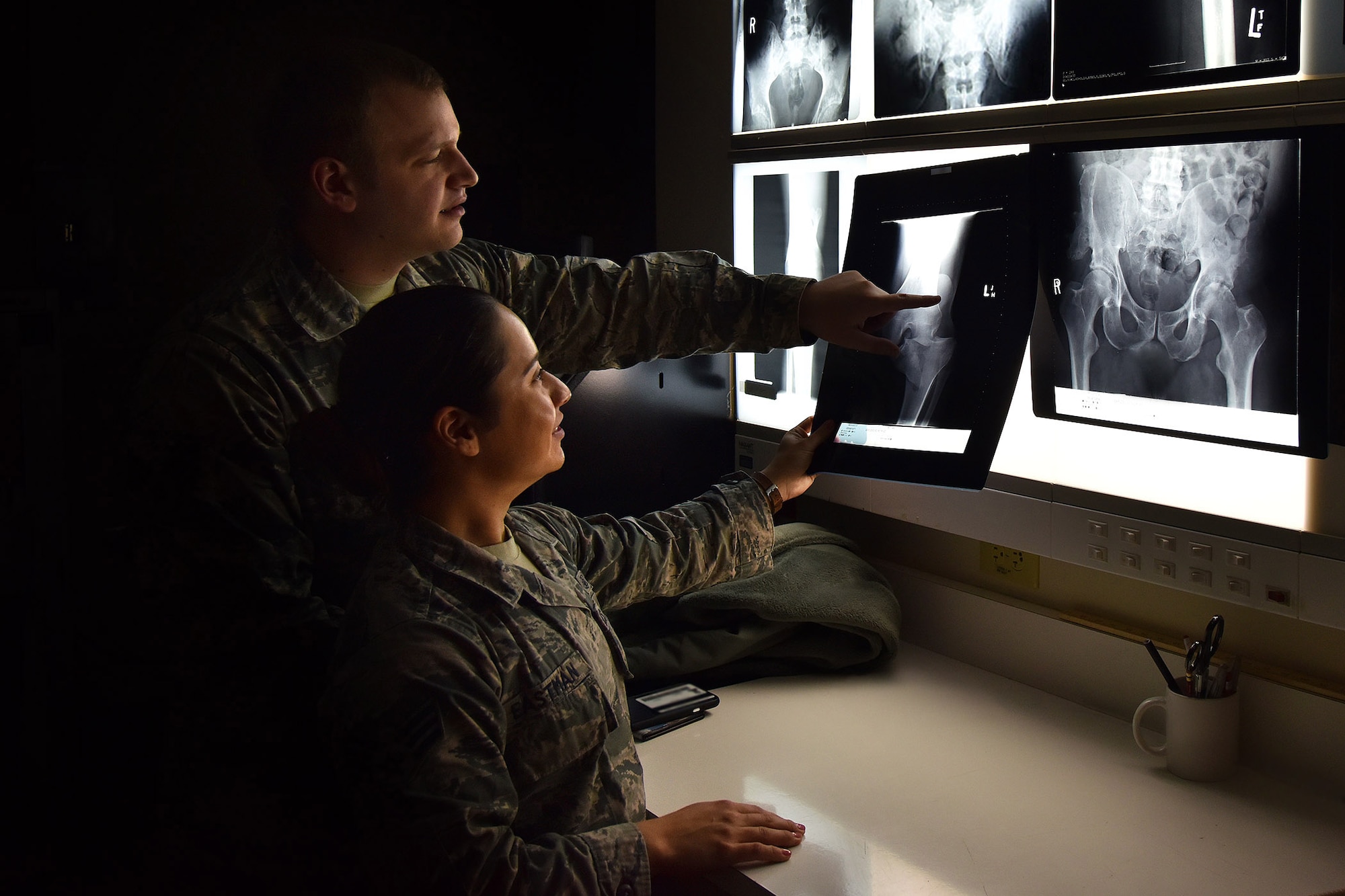 Senior Airmen Joseph Broyles and Sarai Eastman, 341st Medical Group diagnostic imaging technologists, examine X-rays at the clinic, Nov. 6, 2018, at Malmstrom Air Force Base, Mont. After the technicians review the X-rays for accuracy, they send the images to the radiologists at the Air Force Academy for further examination. (U.S. Air Force photo illustration by Airman 1st Class Jacob M. Thompson)