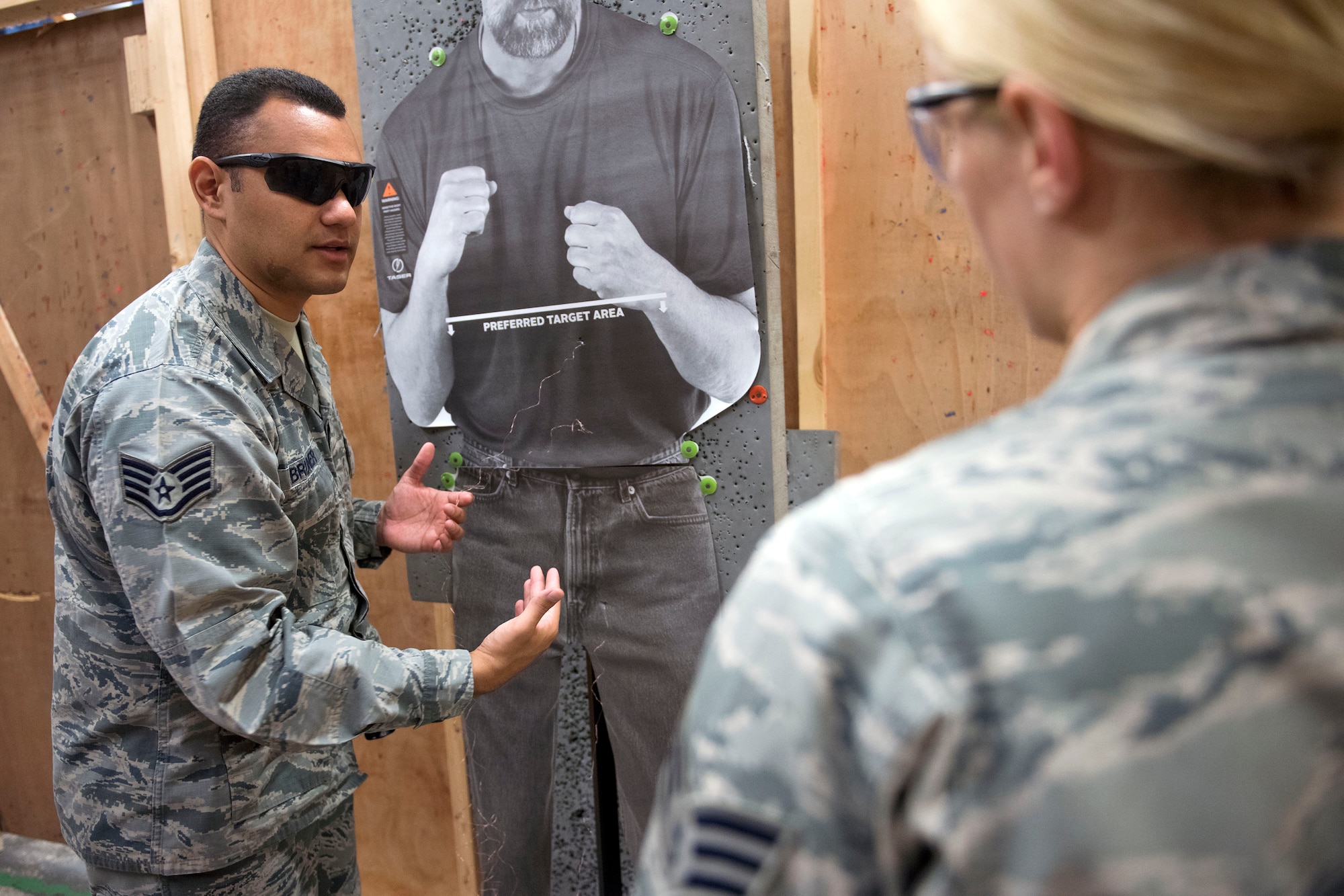 U.S. Air Force Staff Sgt. Anthony Bruner, 100th Security Force Squadron trainer, explains his evaluations of Senior Airman Olivia Krajca’s shots at RAF Mildenhall, England, Nov. 8, 2018. At the minimum Airmen on duty are required to don a baton, and have the option to carry a Taser. (U.S. Air Force photo by Staff Sgt. Christine Groening)