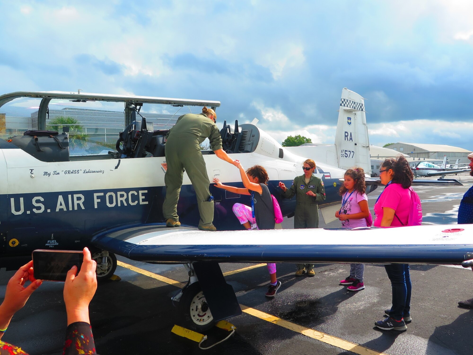 Capt. Julie Rainwaters helps a young girl up onto the wing of a T-6 Texan II.