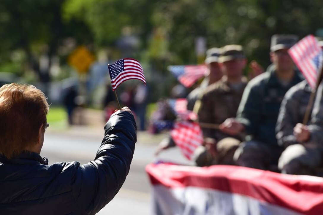 An attendee to Del Rio, Texas’ Veterans Day Parade waves a flag towards a float of service members, Nov. 11, 2018. Laughlin Air Force, Base, Texas, and the local community of Del Rio, Texas, got together to celebrate all who have served through the town’s tradition of a Veteran’s Day Parade. The parade contained many floats featuring not only representatives of Laughlin, but also various veterans’ organizations, vans and ROTC units.