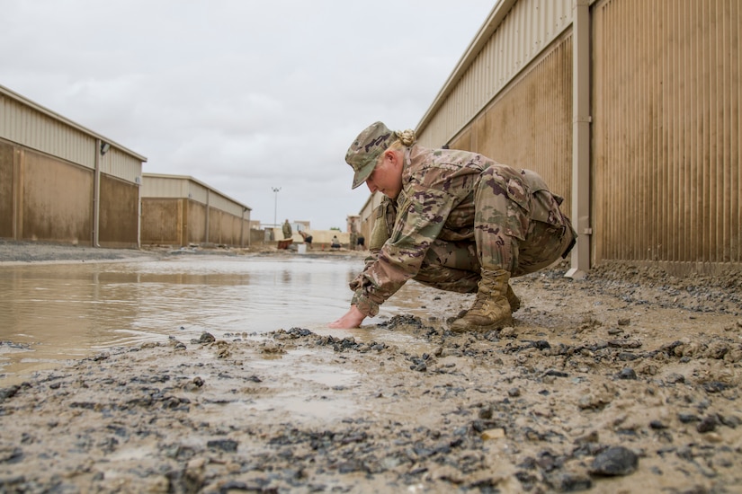 Spc. Nisreen Isbell, a chemical, biological, radiological, and nuclear (CBRN) specialist with the 637th Chemical Company digs a trench with her hands to divert flood waters after a rainstorm at Camp Arifjan, Kuwait, November 11, 2018.The flooding came after an unusually heavy rainstorm hit the area, which has already experienced significant rain this month.
