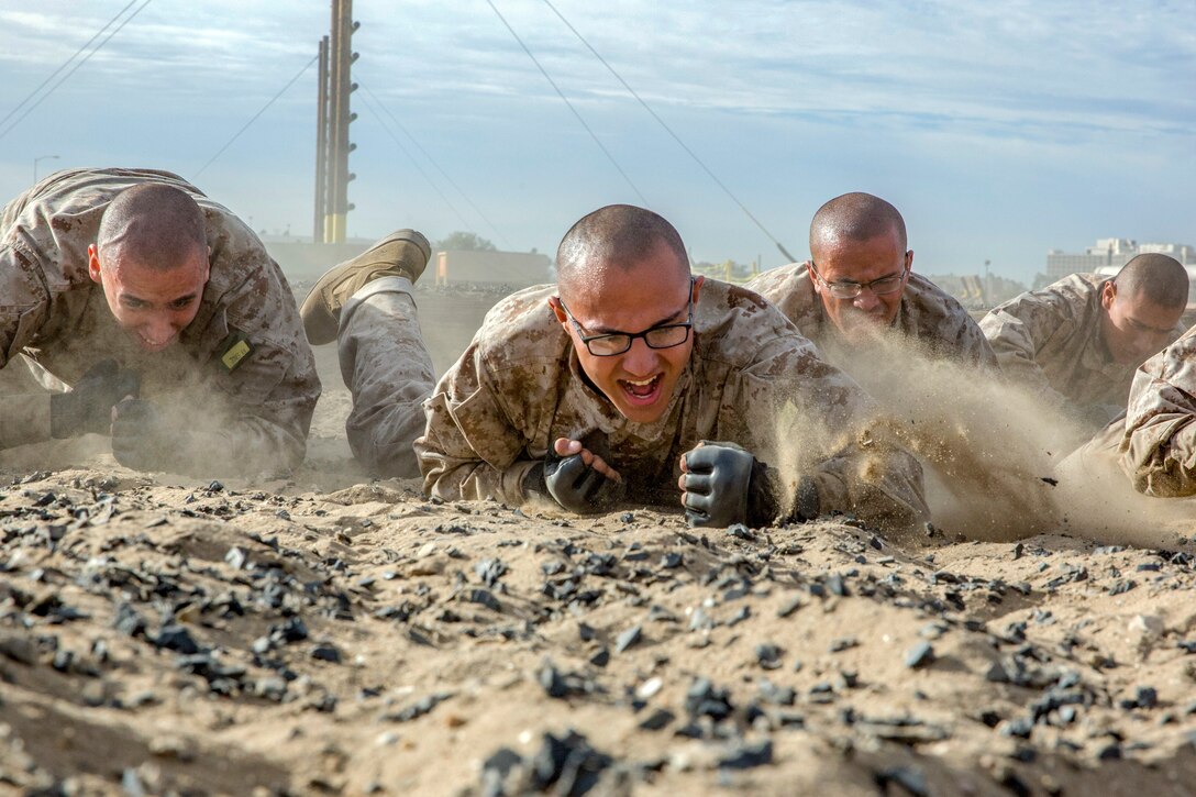 A group of men crawl on dirt.