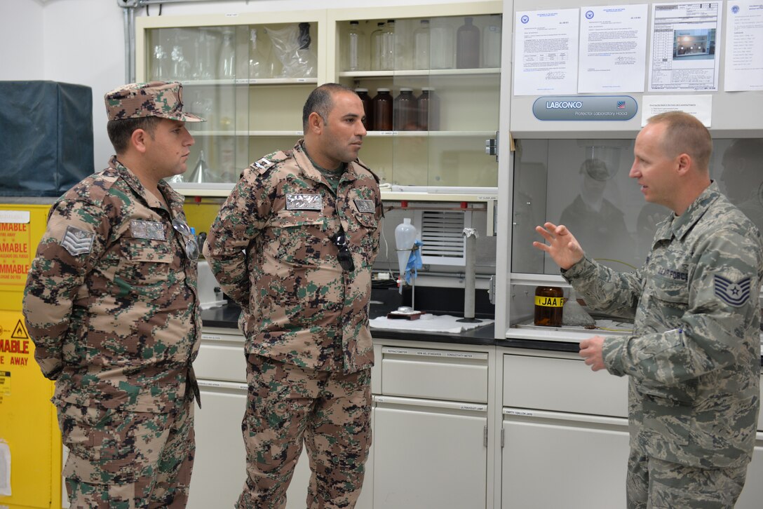 Airman talks to two Jordanian Air Force members in a fuel lab