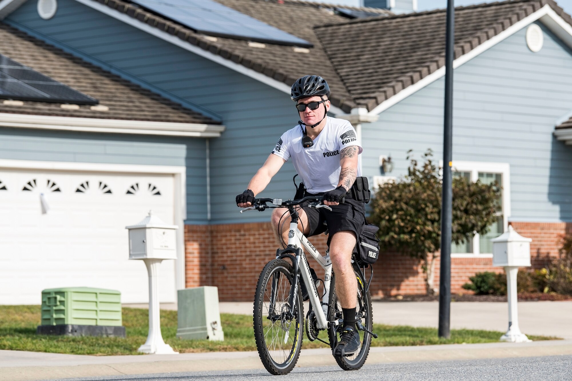 Airman 1st Class Hunter Mowery, 436th Security Forces Squadron response force member, patrols the family housing area on his bicycle Oct. 25, 2018, at Dover Air Force Base, Del. Bike patrol members wear a highly-visible white shirt with “police” stenciled on the back, blue shorts, ride a mountain bike equipped with police lights and saddle bags with “police” stenciled on them