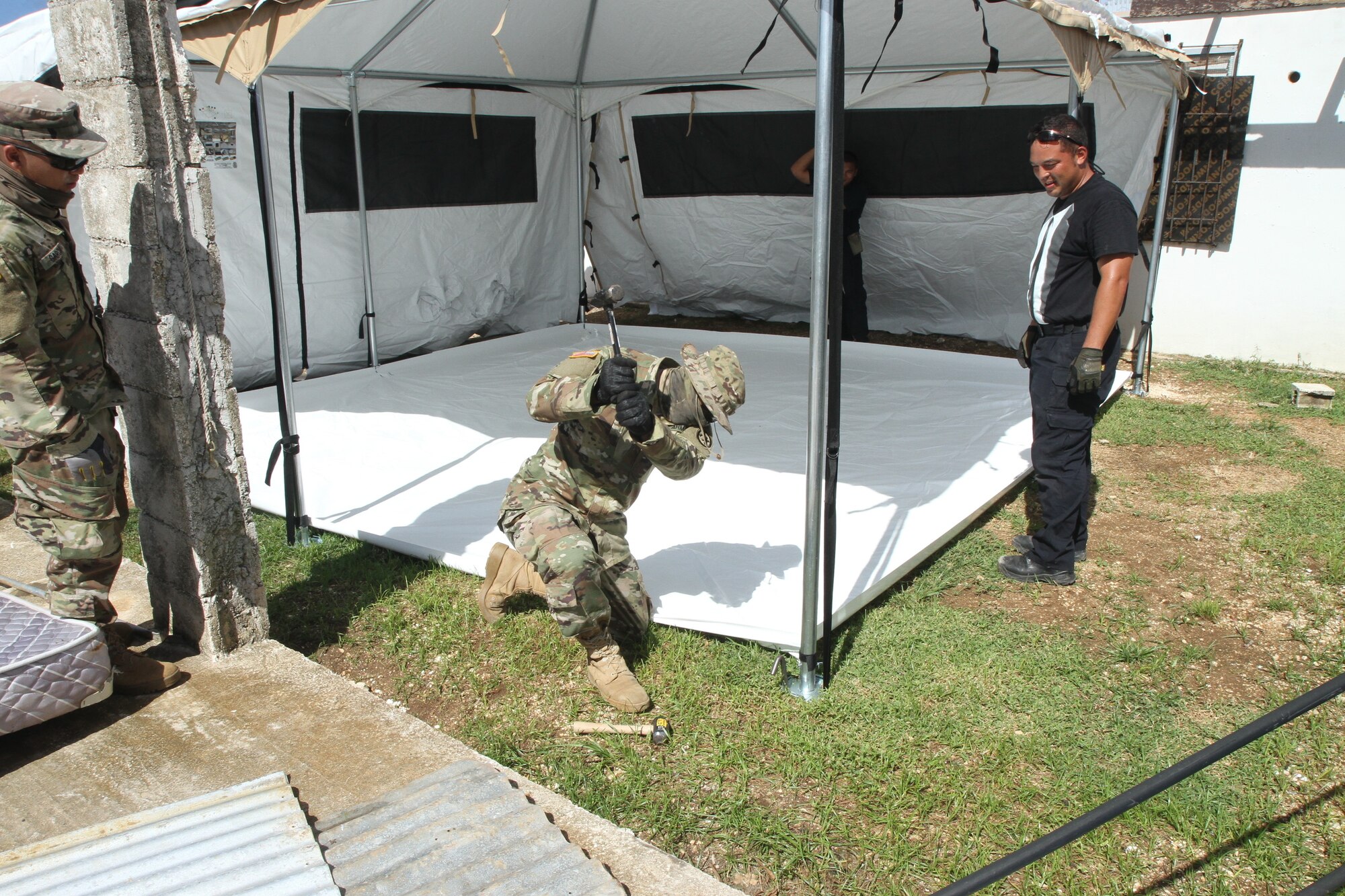 U.S. Army Spc. John Blas, a Soldier with the 797th Engineer Company (Vertical), 9th Mission Support Command, currently assigned to Joint Task Group-Saipan, Task Force-West, stakes a metal rod into the ground to secure a FEMA tent, which will be used as temporary shelter for Saipan residents impacted by Typhoon Yutu, Nov. 9, 2018.