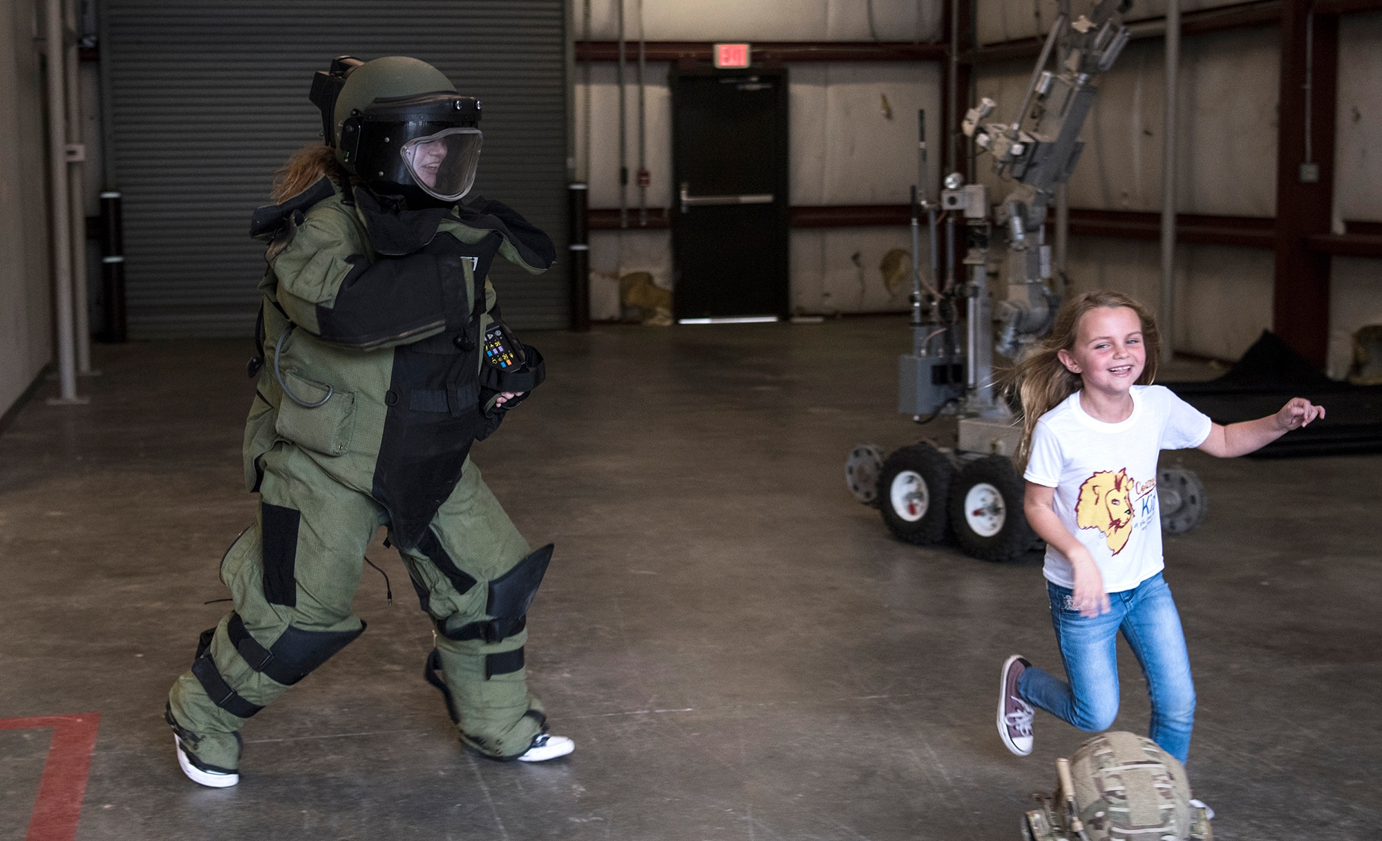 Fallon Emery, a new honorary member of the 437th Operations Support Squadron, chases her sister Mae while wearing an explosive ordnance disposal protective suit Nov. 7, 2018, at Joint Base Charleston, S.C., as part of the Airman for a Day program.