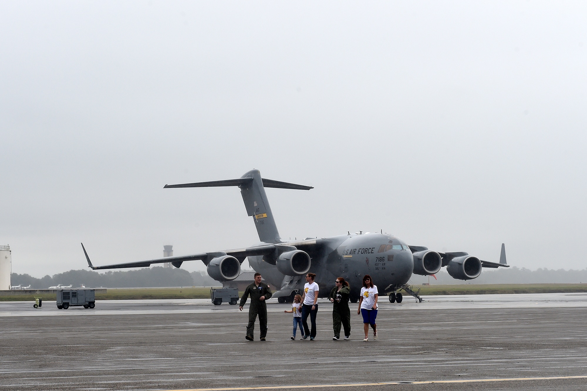 Fallon Emery, second from right, a new honorary member of the 437th Operations Support Squadron, walks on the flight line with 1st Lt. Thad Sollick, left, a C-17 Globemaster III pilot assigned to the 437th OSS, Nov. 7, 2018, after touring a C-17 at Joint Base Charleston, S.C., as part of the Airman for a Day program.