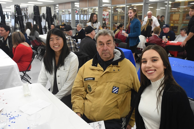Philip Schubitz, center, Vietnam-era veteran who served with the U.S. Army from 1968 to 1970, pauses for a photo with student Lauren Oda (left) and Jessica Pavliukovecas, during the Elk Grove High School Veterans Day ceremony, Nov. 9, 2018.