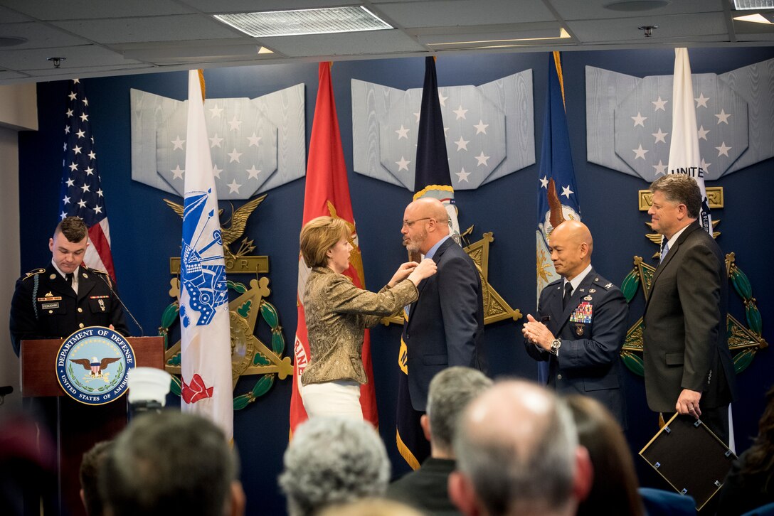 One person pinning an award on another person
