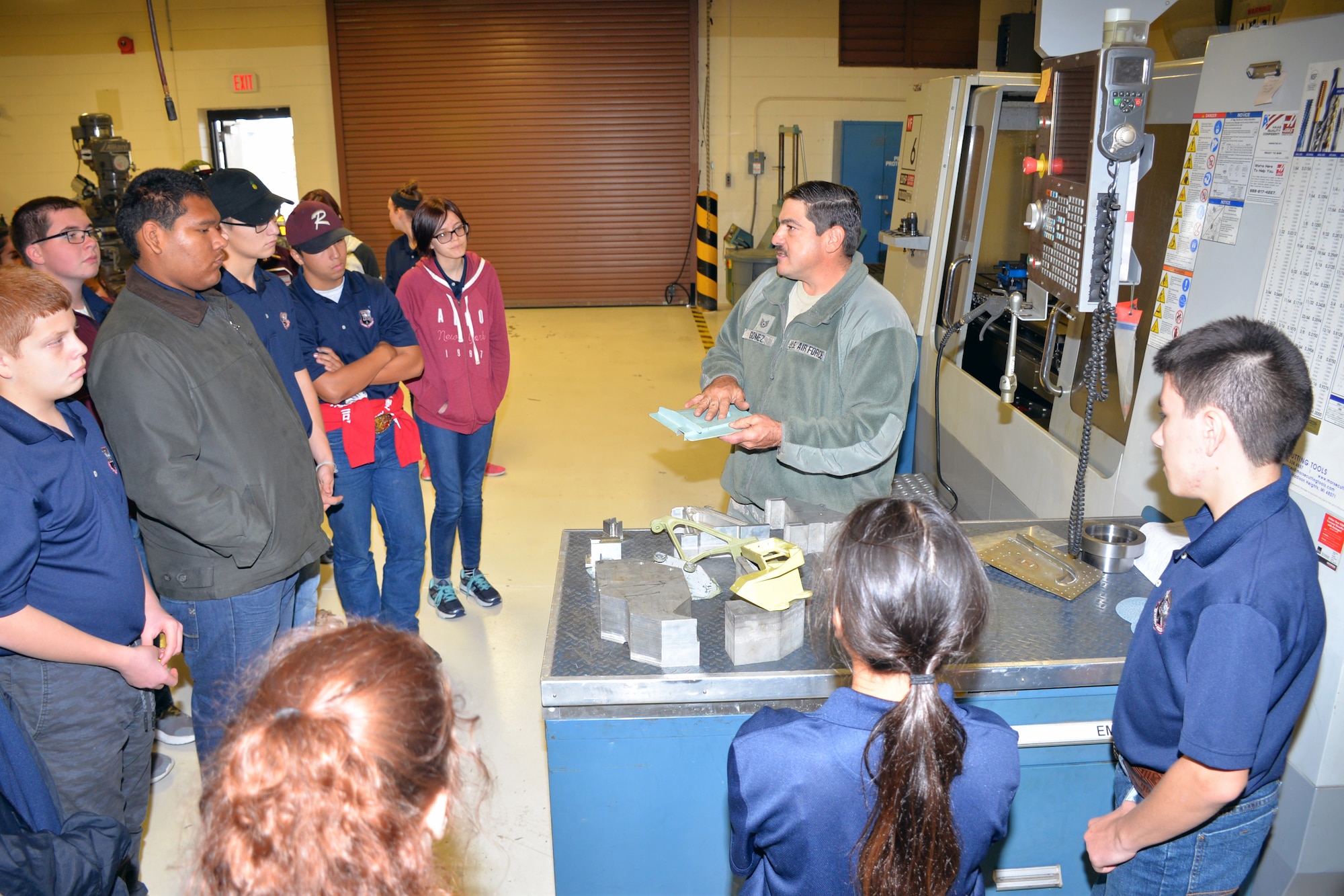 Tech. Sgt. James Gomez, 433rd Aircraft Maintenance Squadron machinist and welder, describes how a computer numerical control machine is used to create replacement parts for the C-5M Super Galaxy to Rowlett High School Air Force Junior Reserve Officer’s Training Corps cadets at Joint Base San Antonio-Lackland, Texas Nov. 9, 2018.